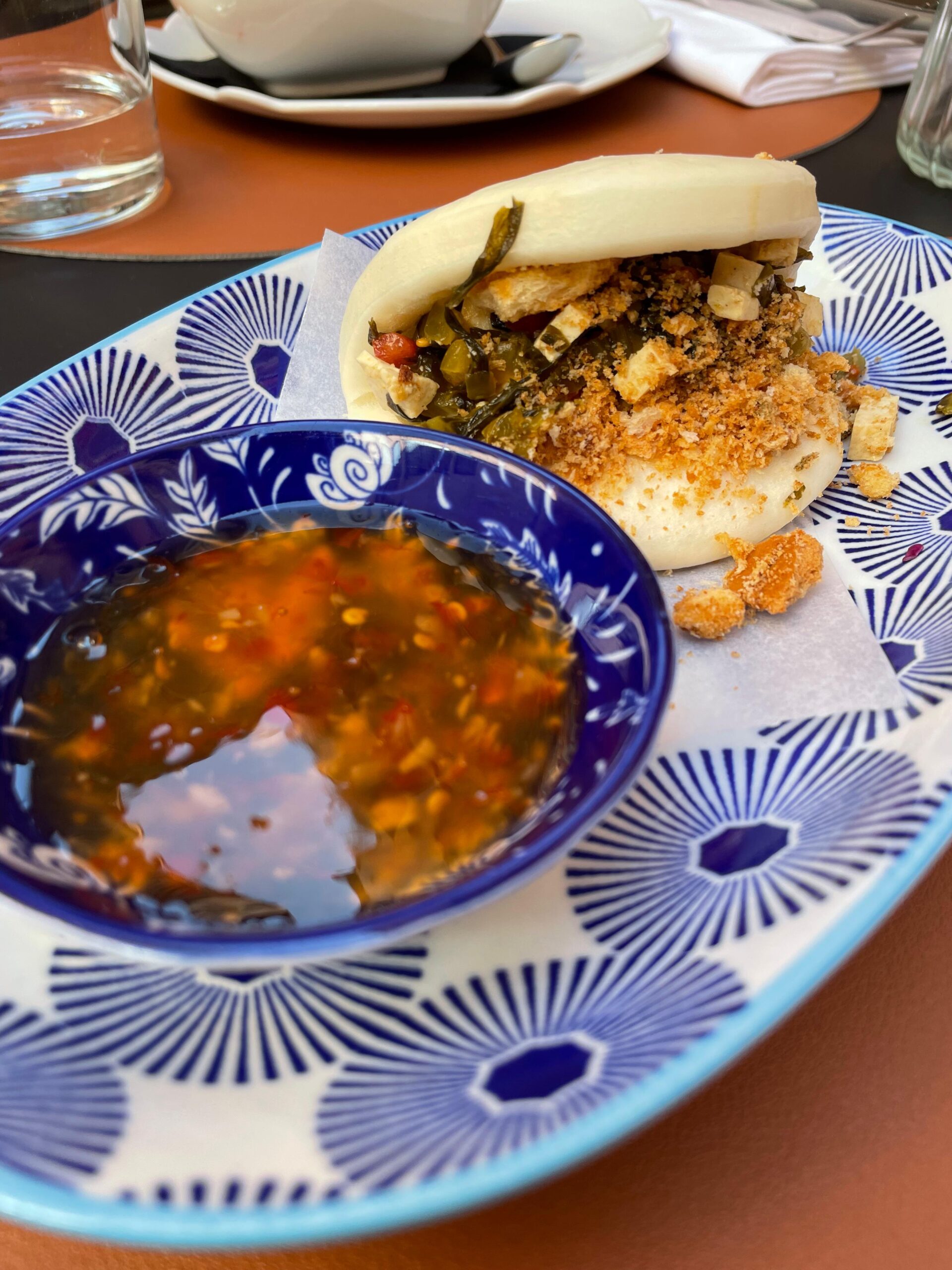 Bao, arricchito da foglie di senape marinate, tofu, pomodorini e tarallo sbriciolato di Amo Bistrot